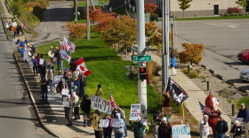 Ralliers stand at the street corner of Hiawatha Blvd. and Solar Street in Syracuse holding signs urging passersby to vote early.