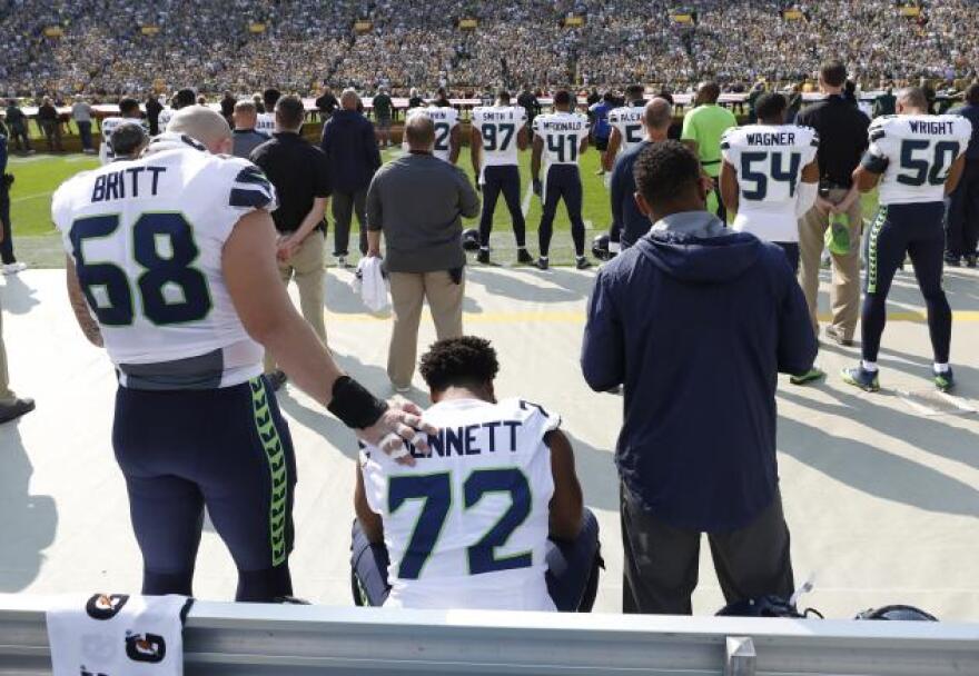 Seattle Seahawks' Michael Bennett remains seated on the bench during the national anthem before an NFL football game against the Green Bay Packers Sunday, Sept. 10, 2017, in Green Bay, Wis.