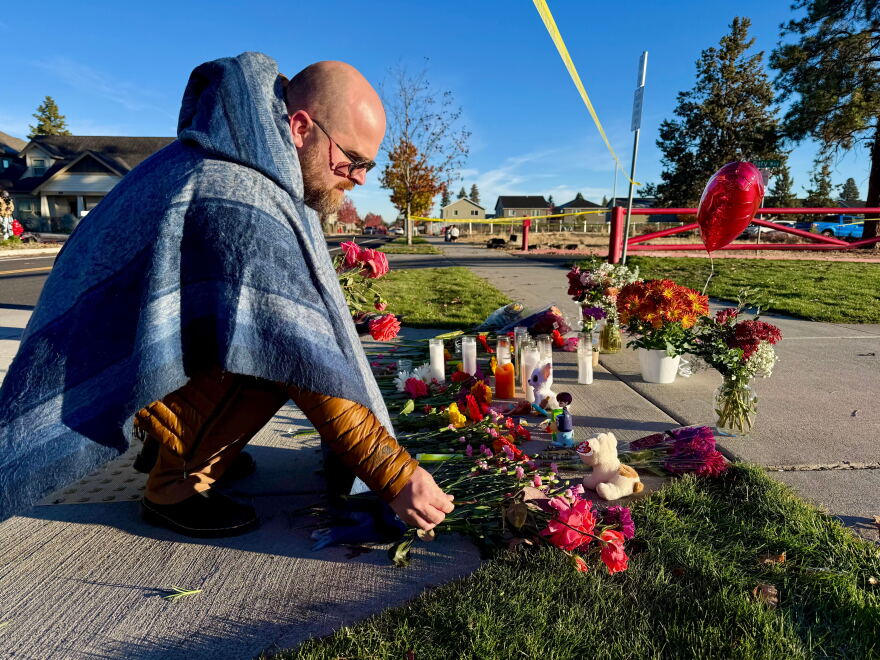 A person places flowers at a makeshift memorial on the other side of Silver Rail Elementary School in Bend, Ore., on Friday, Oct. 16, 2026, a day after a deadly shooting. (AP Photo/Haven Daley)