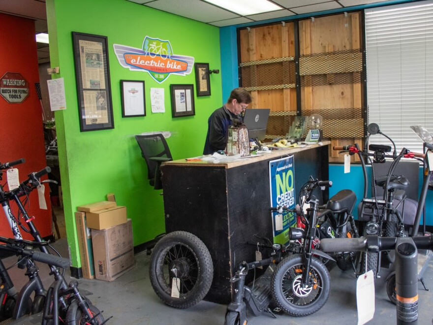 The Electric Bike Shop owner Mike Majors stands behind his desk Monday, Nov. 17, 2025, at 5704 Broadway in Sacramento.