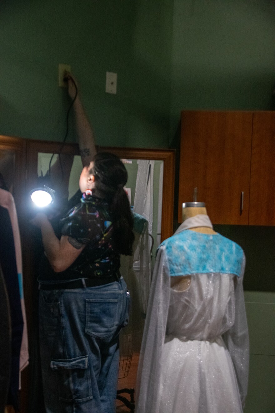 Costume designer Sarah Talavera-Moloney plugs in an LED stage light inside the dressing room in the costume shop to test the look of a garment under the light.