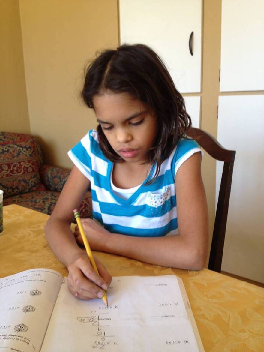 Fourth grader Isa Ruegger completes a page in her workbook at home.