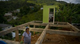 In this Sept. 8, 2018 photo, Alma Morales Rosario poses for a portrait between the beams of her home being rebuilt after it was destroyed by Hurricane Maria one year ago in the San Lorenzo neighborhood of Morovis, Puerto Rico.