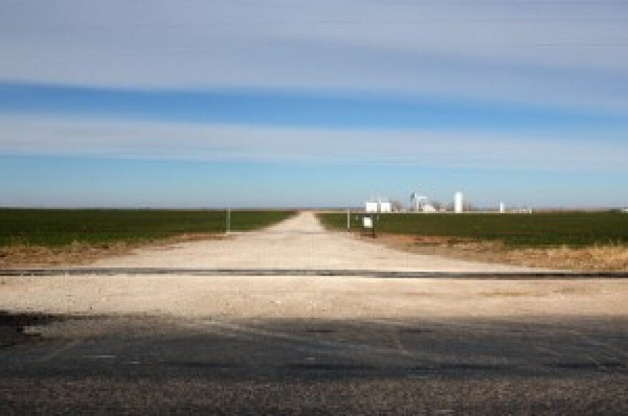 A water line for hydraulic fracturing crosses an oil-field access road in Woods County, Okla.