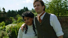 A man and a woman embrace in period clothes