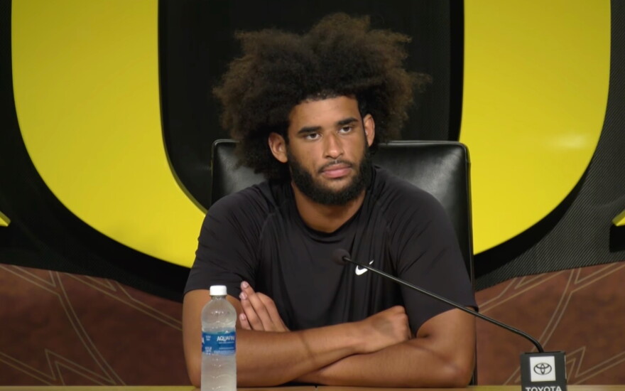 A man sits at a table in front of a microphone