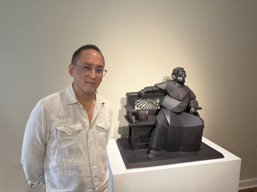Artist Warren King stands next to his cardboard sculpture titled "The Emperor Takes Five."