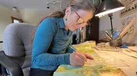 Artist Nancy Bernstein traces over a detail on a map from the Adirondack Park Agency to add to her map for Historic Saranac Lake.