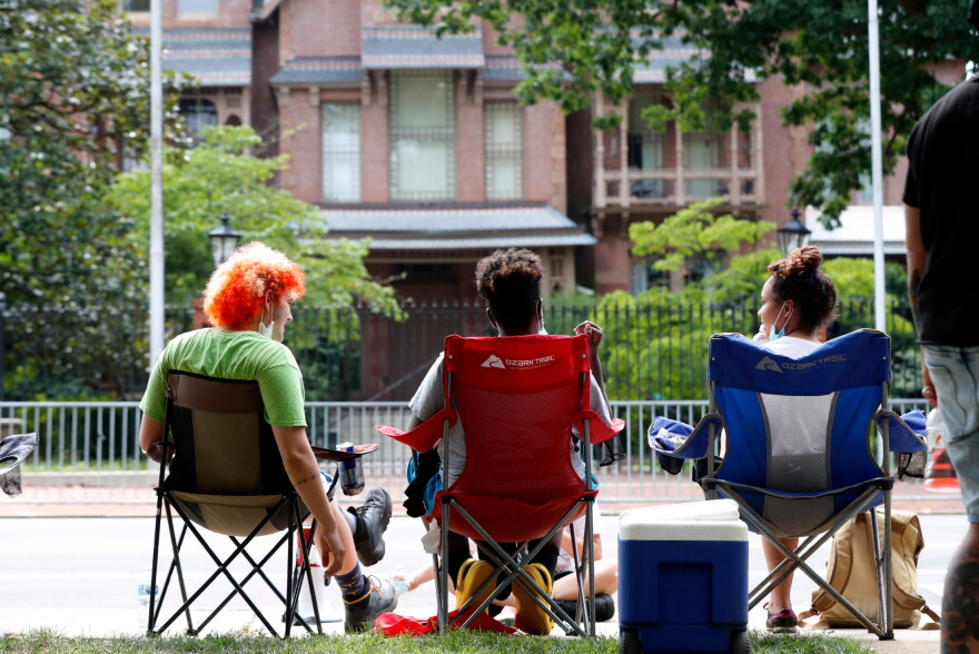 Protesters sit outside the N.C. Executive Mansion in Raleigh, N.C., Tuesday morning, June 30, 2020. They camped out overnight Monday to protest a new bill that further limits public access to death investigation records.