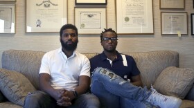 posed photo of rashon nelson and donte robinson sitting on a sofa, the wall behind them hold many diplomas etc.