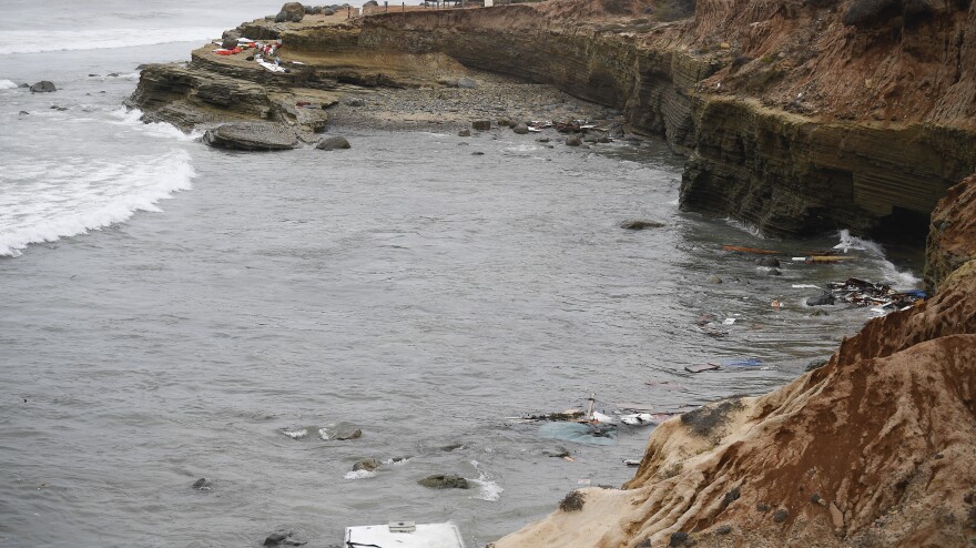 Wreckage from a capsized boat washes ashore at Cabrillo National Monument near where a boat capsized off the San Diego coast Sunday. Authorities say three people were killed and two dozen others injured.