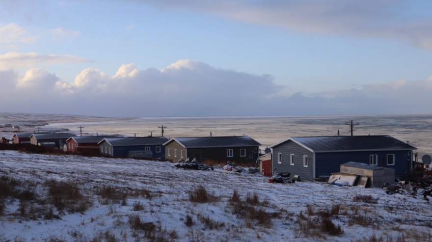 A row of houses stand along a river in Western Alaska