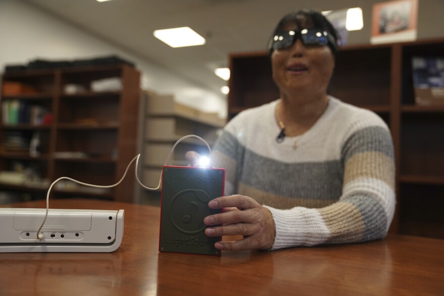 Minh Ha, assistive technology manager at the Perkins School for the Blind tries a LightSound device for the first time at the school's library in Watertown, Mass., on March 2, 2024. As eclipse watchers look to the skies in April 2024, new technology will allow people who are blind or visually impaired to hear and feel the celestial event.