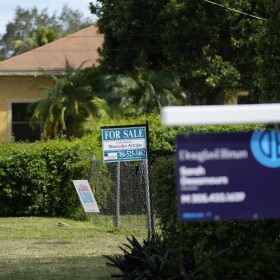 FILE - Realty signs indicating homes for sale hang in front of properties in the Coconut Grove neighborhood of Miami. (AP Photo/Rebecca Blackwell)