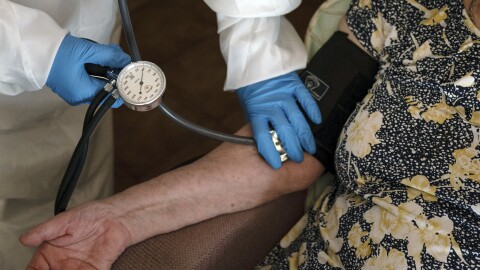FILE - A doctor checks the blood pressure of a patient.