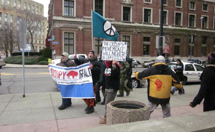 Occupy Buffalo members march outside Buffalo City Court shortly after the arraignment of ten members. They agreed to a deal in which charges will be dropped in six months if they do not camp within three miles of Niagara Square and stay out of trouble.