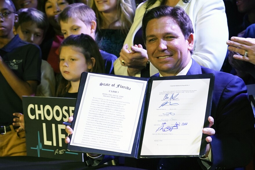 FILE - Florida Gov. Ron DeSantis holds up a 15-week abortion ban law after signing it on April 14, 2022, in Kissimmee, Fla. The law banning the procedure in most cases after 15 weeks of pregnancy goes into effect Wednesday.