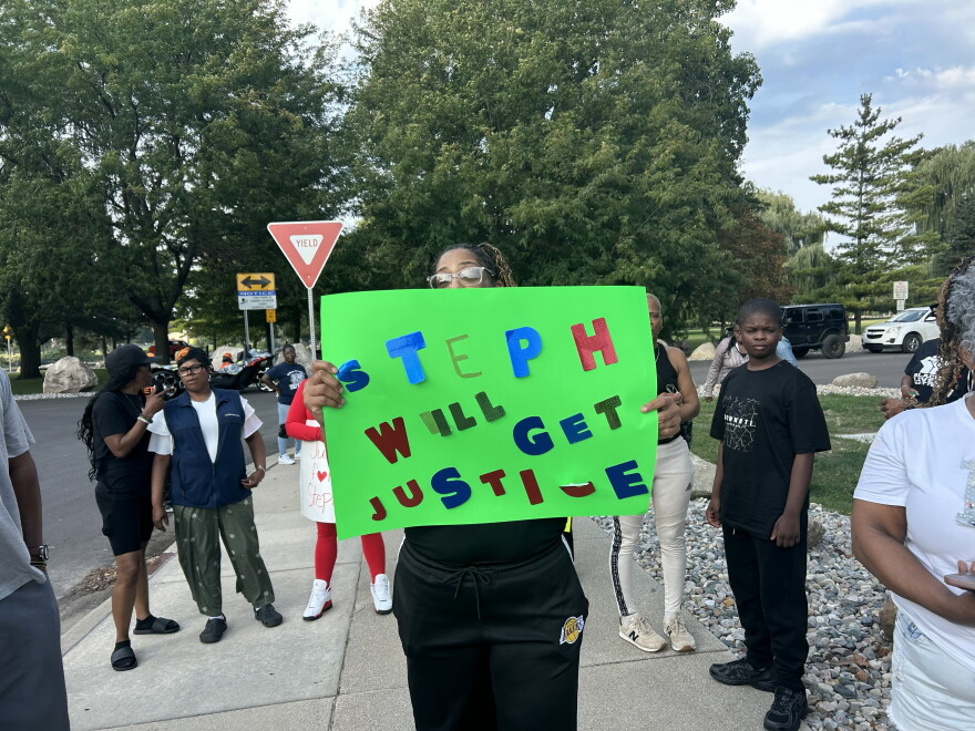 A woman displays a "Step will get justice" sign near Ojibway Park in Saginaw, Mich. on Monday, Aug. 31, 2026 ahead of the Saginaw city council meeting.
