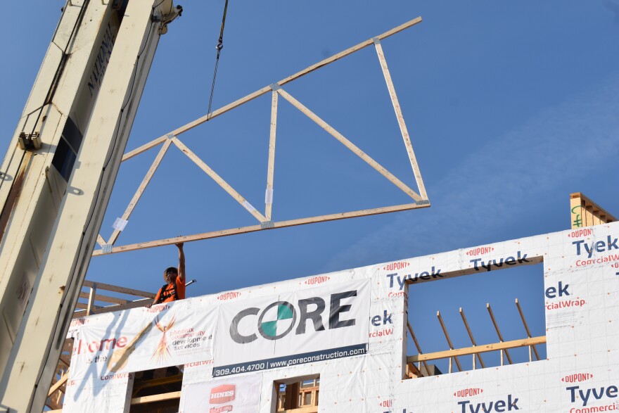 A construction worker guides a signed truss hoisted up by a crane into place on the fourth floor of the Madison North Apartments development. The apartments for people experiencing homelessness are expected to open next February.