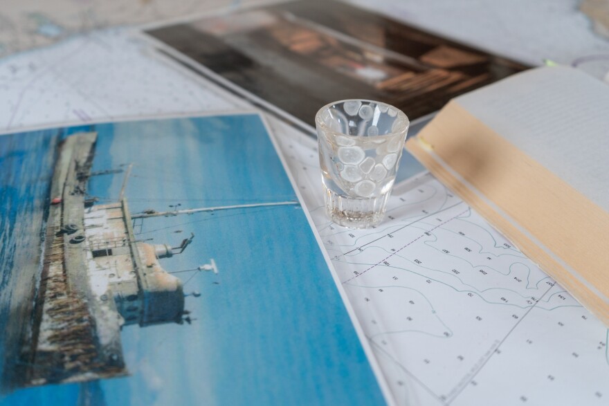 A shot glass sits between a book and a photograph on a table.