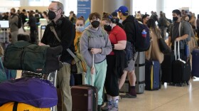 Travelers wait in the ticketing line at Salt Lake City International Airport on Monday. There have been thousands of flight delays and cancellations as the omicron variant spreads across the country. Unionized flight attendants are wary of new CDC guidelines that shorten the isolation period.