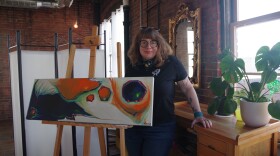Artist Kim Shaw stands with her painting.