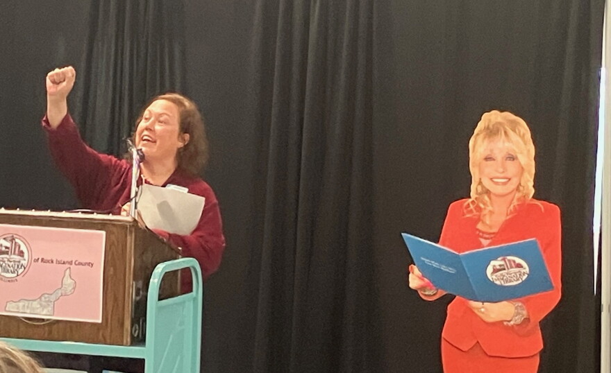 Rock Island Public Library director Angela Campbell, with a cutout of Dolly Parton (at right) announces a $36,205 fundraising campaign to relaunch Dolly's Imagination Library in the county.