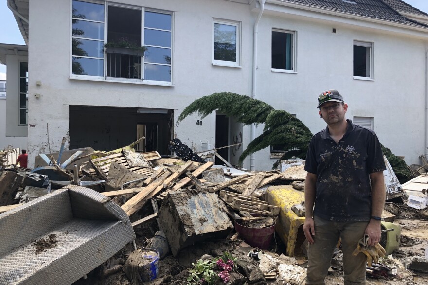 Martin Larsson stands by the debris in front of his damaged home.