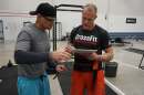 Two ment stand in a gym near weights and other workout gear