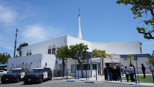 FILE - People gather as police vehicles are parked outside of the Islamic Center of San Diego, the day after a shooting, May 19, 2026, in San Diego.