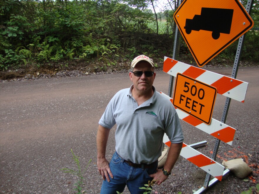 Tim Ziegler next to construction sign on dirt road.