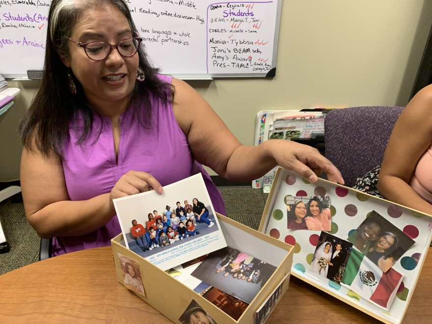 Educator Monica Hughes holds up a box displaying personal photos.