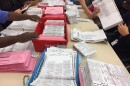 Election workers sort through unprocessed vote-by-mail ballots at the Sacramento County Registrar of Voters office on Monday.