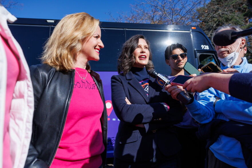 Democratic gubernatorial nominee Jocelyn Benson, left, and Gov. Gretchen Whitmer, right, speak with reporters in East Lansing, Mich., during the first stop on Benson's statewide "Driving Down Costs" bus tour on Oct. 22, 2026.