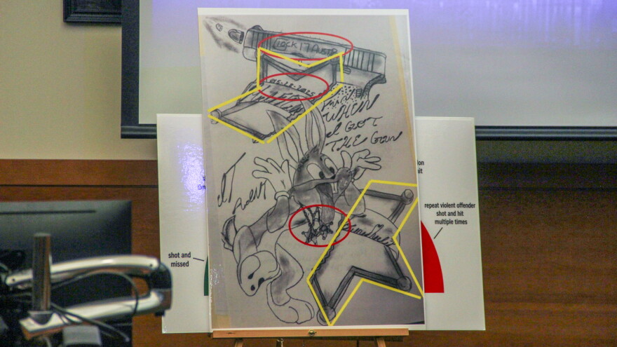 A poster-board sized print of a drawing showing a cartoon rabbit sticking his tongue out. The rabbit wears two police badges and appears between broken halves of a larger police badge. The date 5/28/5 appears on the top half of the bade. On the sides, the words, "it ain't fun when I got the gun." 