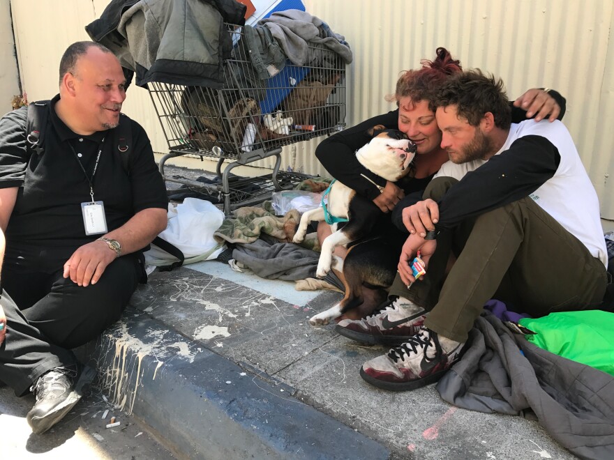 Eric Smith, left, talks to a homeless couple in San Francisco during neighborhood rounds. He's patient coordinator at the Haight-Ashbury Free Clinics, and wants to make sure they know they can get health care and addiction treatment there.