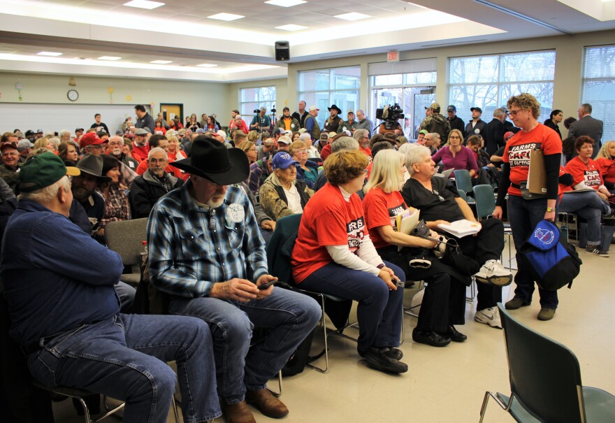 At a public hearing on the proposed Valley Oaks cattle feedlot expansion, rancher Kevin Mannering (left) wears a sticker that reads 'YES... Family Farms' in support. Several people donned red shirts reading 'Farms Not Factories' to show their opposition.