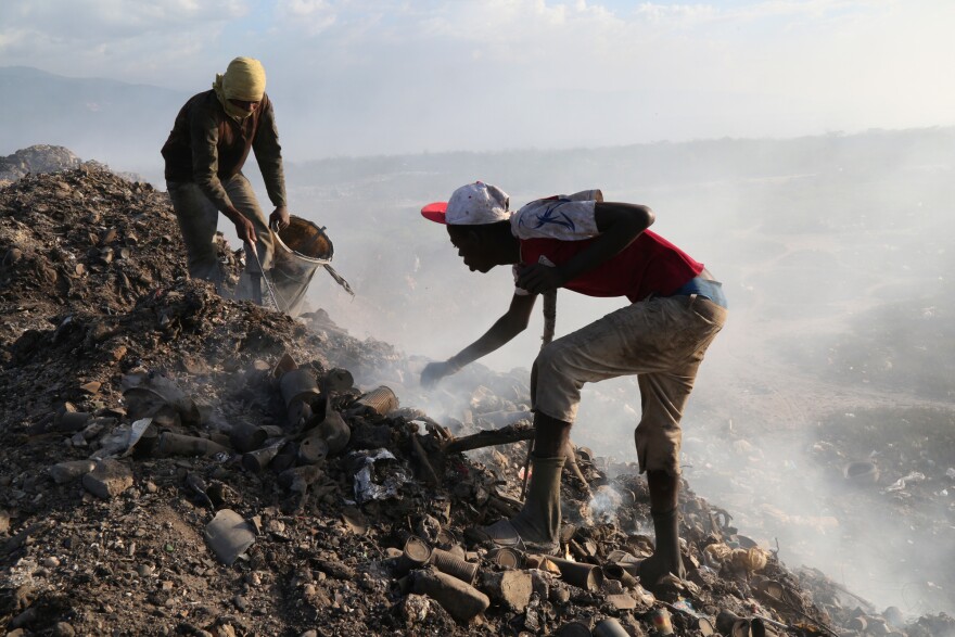 At the city landfill, men look for metal near the edge of a pit that used to be full of raw sewage. Construction delays at the Titanyen sewage treatment plant meant that raw sewage continued to be dumped at the landfill for months after the cholera epidemic began in 2010.