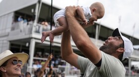 Scottie Scheffler holds his son Bennett Ezra Scheffler as his wife Meredith Scudder looks on the 18th green after Scheffler won the final round of the Tour Championship golf tournament, Sunday, Sept. 1, 2024, in Atlanta. 