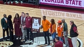 Charlie Ward stands next to a replica of his FSU basketball jersey as he receives center court honors prior to leading his FAMU team against his alma mater.