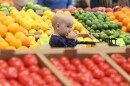 Ten-month-old Juni Riley enjoys a lemon while watching her mom, Lillian Riley, shop for fruit during the opening of the Whole Foods in Brighton on Wednesday, April 12, 2023.