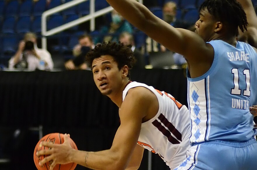 Virginia Tech's Keve Aluma looks to pass around UNC's Day'Ron Sharpe on March 11, 2021 at the ACC men's basketball tournament in Greensboro, N.C.