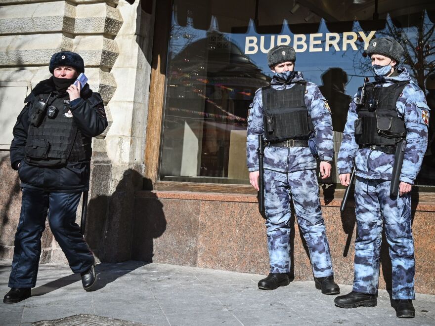 A Russian police officer and national guard servicemen patrol Red Square next to Burberry shop in Moscow on Thursday. The U.K. imposed a new export ban that will likely affect luxury vehicles, high-end fashion and works of art.