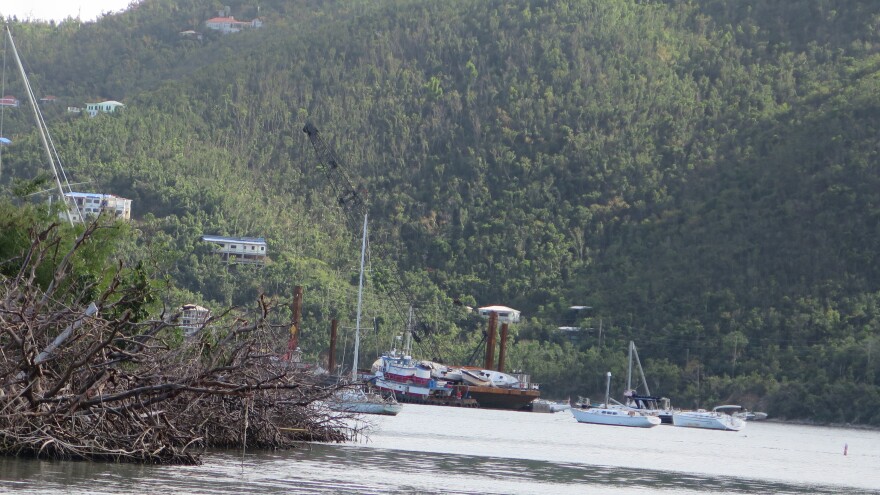 Using a crane, the Coast Guard puts derelict vessels it lifts from the water onto barges. They'll be transported to the mainland for disposal.