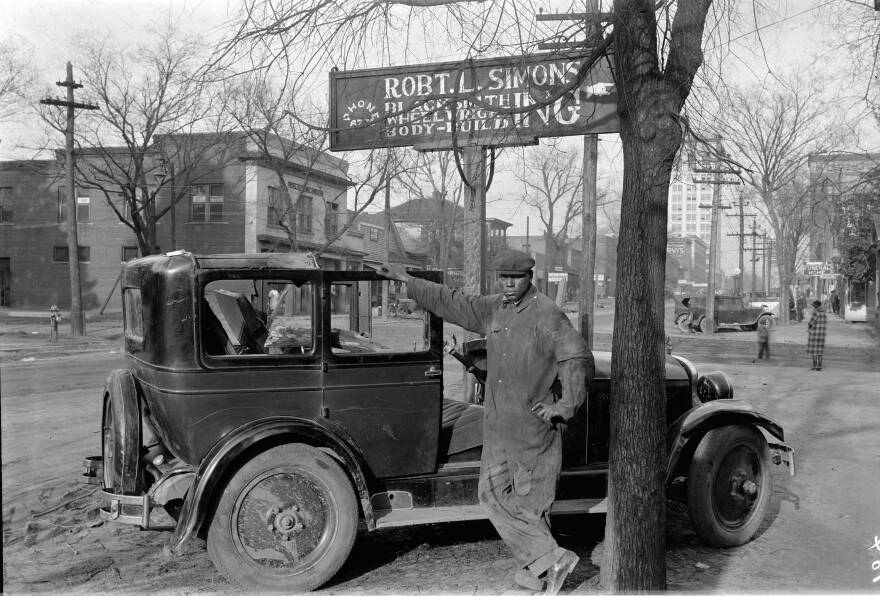 John "Bennie" Taylor was a mechanic at Robert L. Simons' Body Works at 928 Washington Street. Numerous other businesses are visible in the background. Image digitized from glass plate negative.