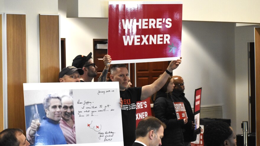 Survivors of Dr. Richard Strauss's sexual abuse at Ohio State University hold up signs asking where Ohio billionaire Leslie Wexner is at an OSU Board of Trustees meeting on Dec. 4, 2025. Wexner, a former friend of the convicted sex offender Jeffrey Epstein, is defying subpoenas to be questioned in a lawsuit against OSU.
