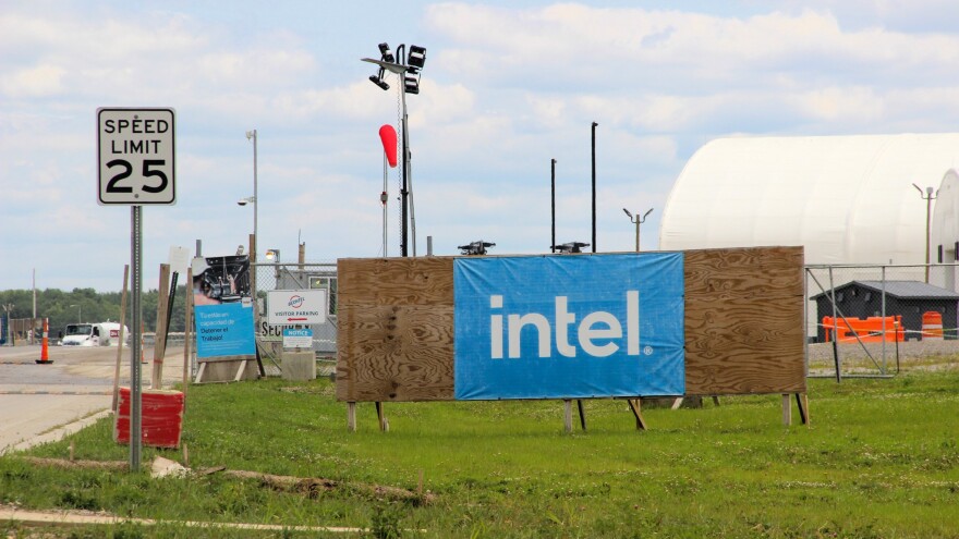 At a construction site, a banner tacked to a large slab of wood reads "Intel." 