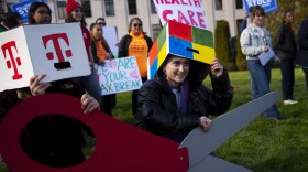Emma LeFever, with Washington CAN, smiles before a group photo is taken following a rally against tax cuts for corporations on Thursday, February 26, 2026, at the Washington State Capitol campus in Olympia. KUOW Photo/Megan Farmer