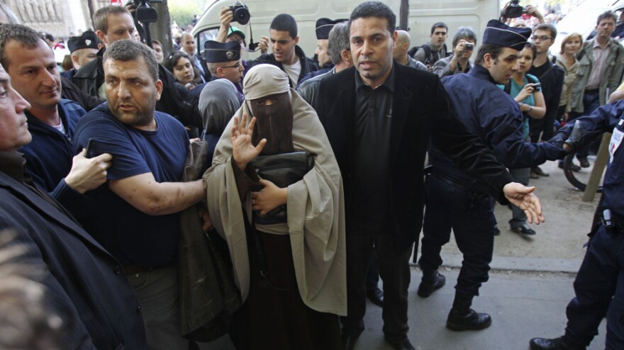An unidentified veiled woman, flanked by friends, was taken away by police officers in Paris earlier today (April  11, 2011). France's new ban on Islamic face veils was met with a burst of defiance, as several women appeared veiled in front of Paris' Notre Dame Cathedral.