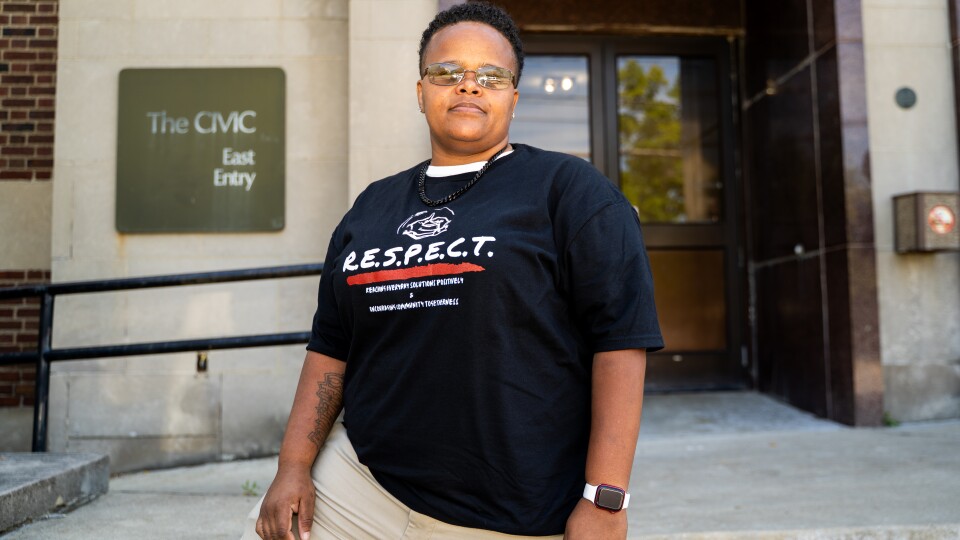 Woman stands on steps of big building.